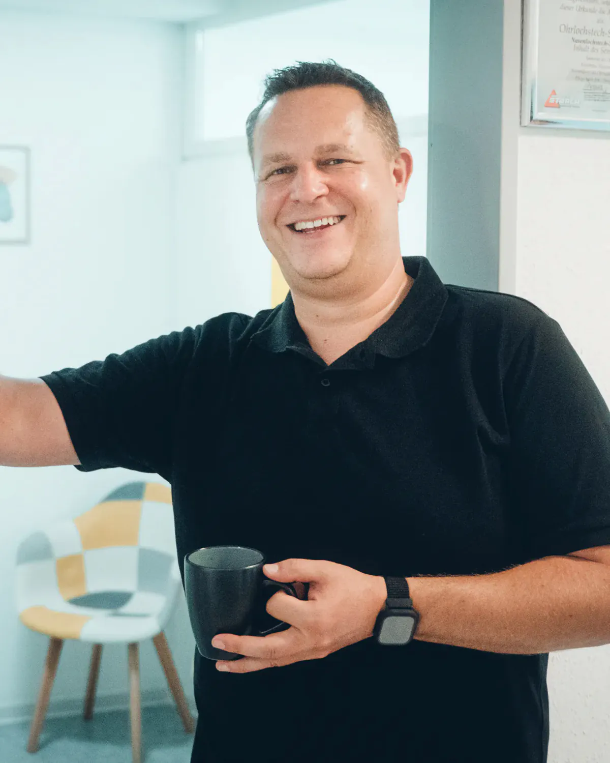 Jörg Goßler mit Kaffeetasse in seiner Praxis – Dein künftiger Arbeitsplatz bei Via Vitales